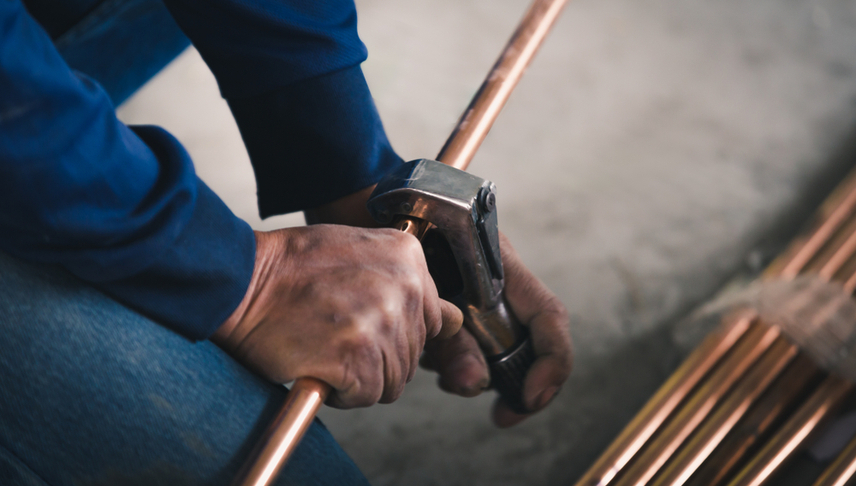 man cutting a copper pipe