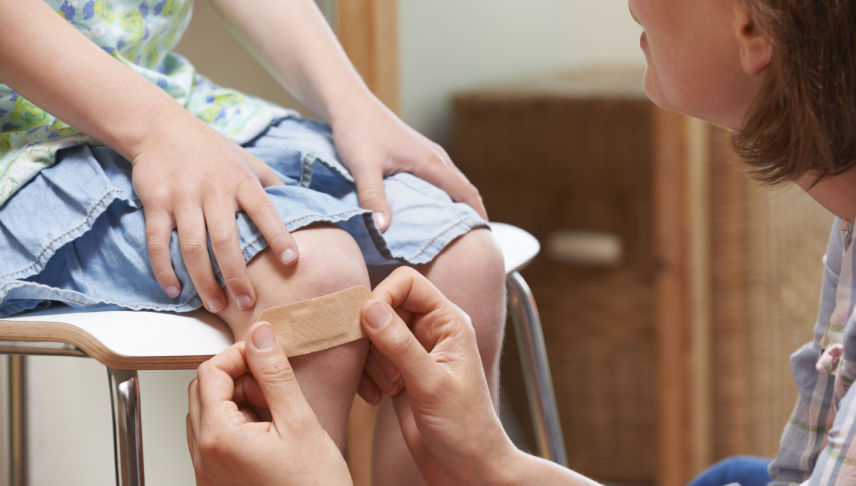 teacher applying adhesive bandage to student at daycare center