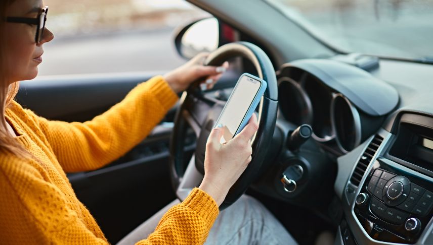 young woman using mobile phone while driving